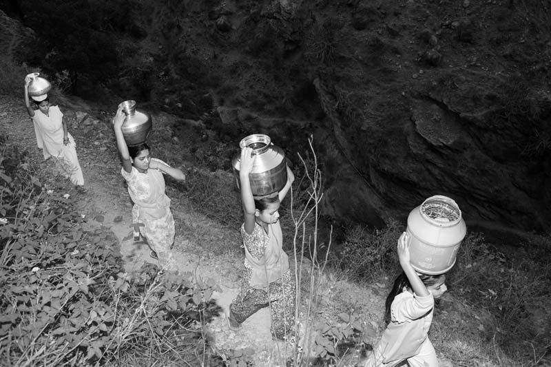 Rural Drinking Water Challenges - Carrying drinking water collected from a distant spring located down the slopes of Himalayan mountains in Tehri Garhwal district, Uttarakhand